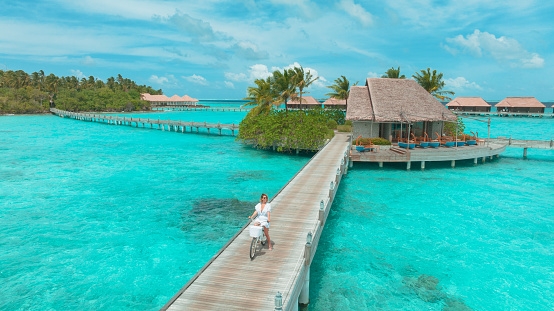 Young woman with bicycle on wooden pier in the Maldives