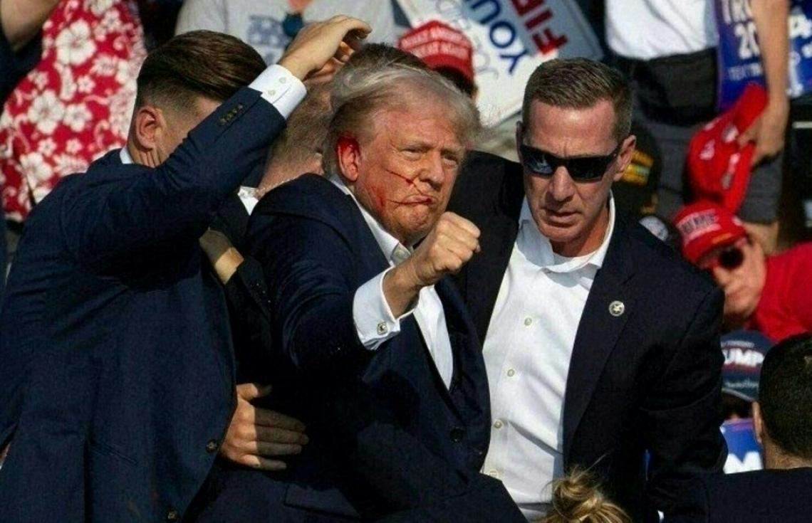 އެމެރިކާގެ ކުރީގެ ރައީސް ޑޮނަލްޑް ޓްރަމްޕުގެ ކެމްޕެއިން ރެލީއެއްގައި ބަޑި ޖެހުމުން ޒަހަމްވުމާ އެކު ސީކްރެޓް ސާވިސްގެ އެޖެންޓުން ޓްރަމްޕް ސްޓޭޖުން ބާލައިގެން ގެންދަނީ. -- ފޮޓޯ: އޭއެފްޕީ